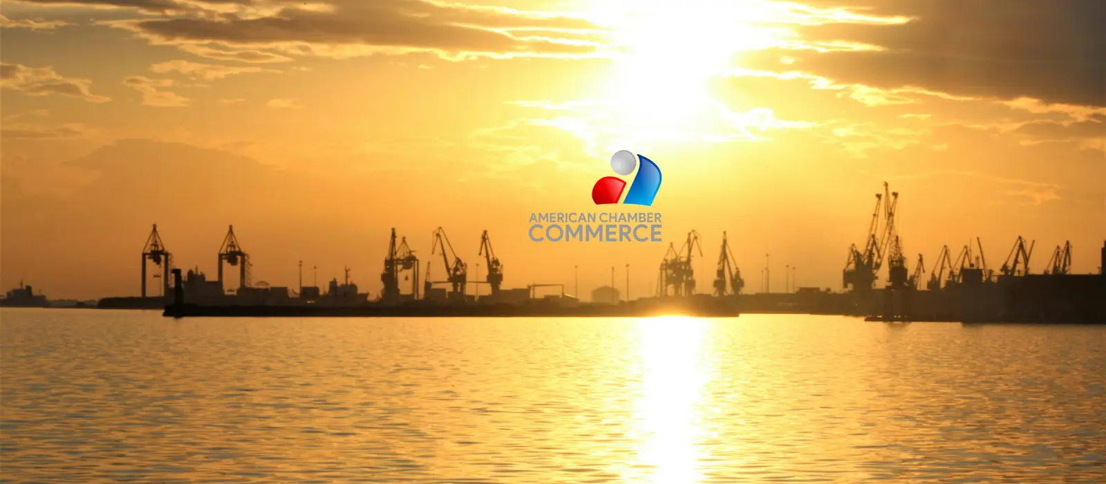 Port cranes silhouetted against a sunset